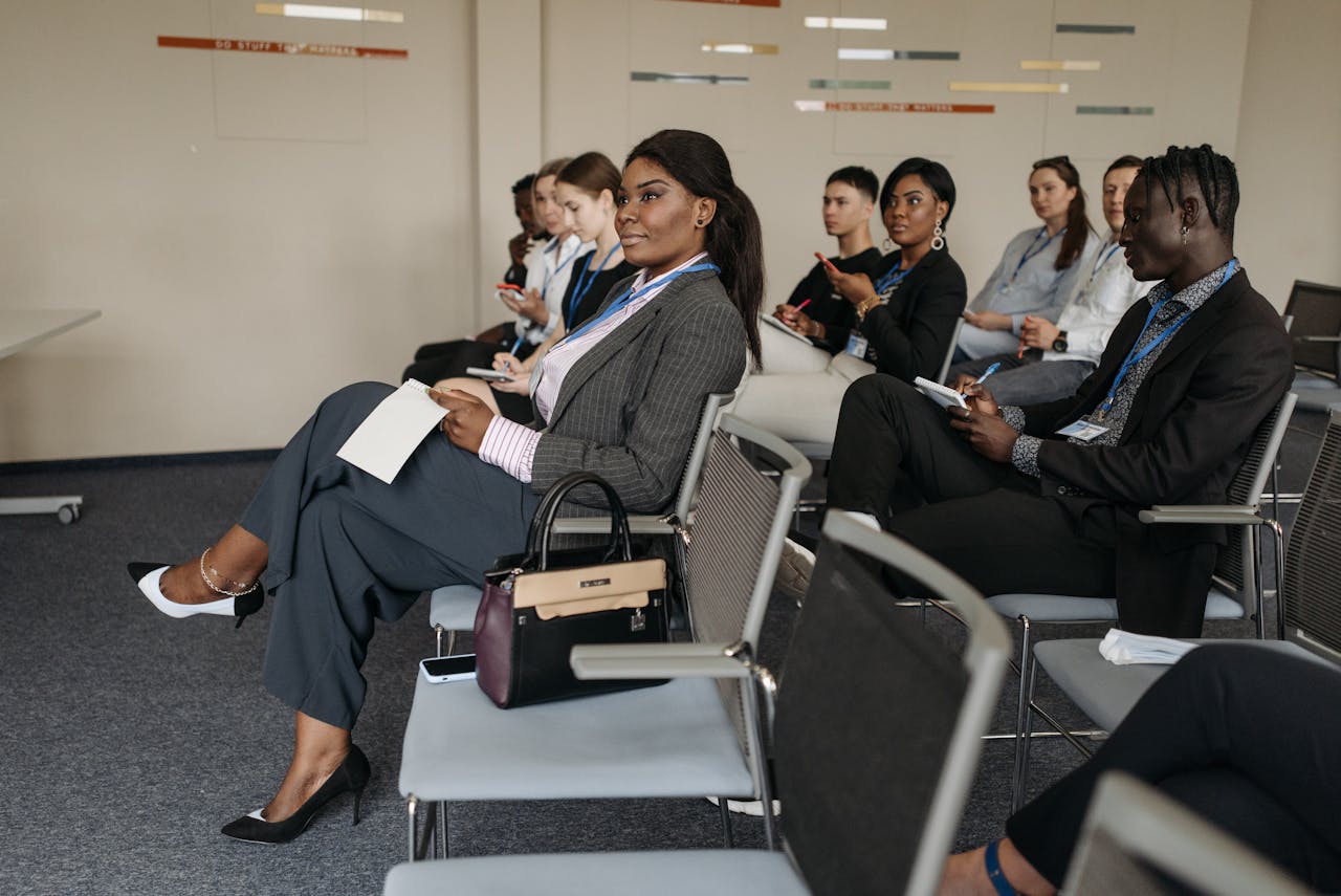 A diverse group of adults engaged in a business seminar, showcasing active listening and participation.
